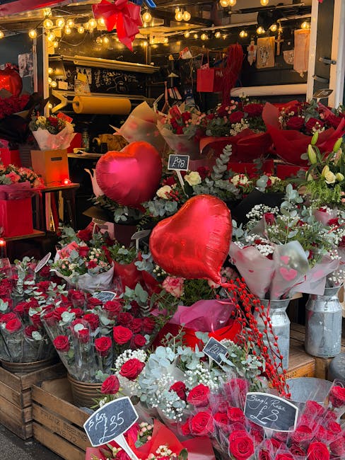 A vibrant floral display at the floristnottinghill.co.uk shop showcases a variety of fresh red and white roses arranged in bouquets and wrapping paper, accented with greenery and decorative elements. 
